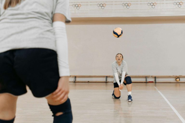 Intense moment of volleyball practice indoors with two women players focusing on the game.